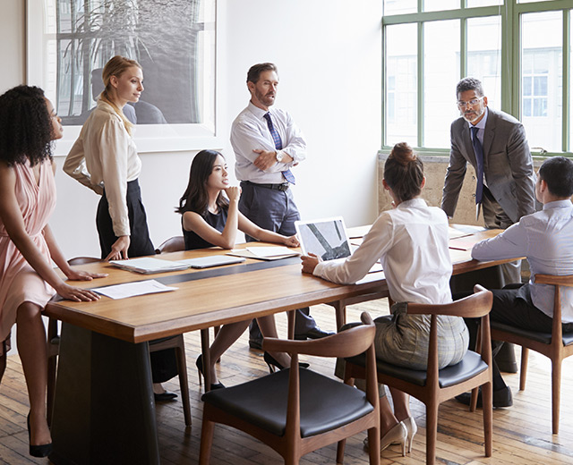 Group of professional business consultants gathered and discussing technology solutions in a business meeting